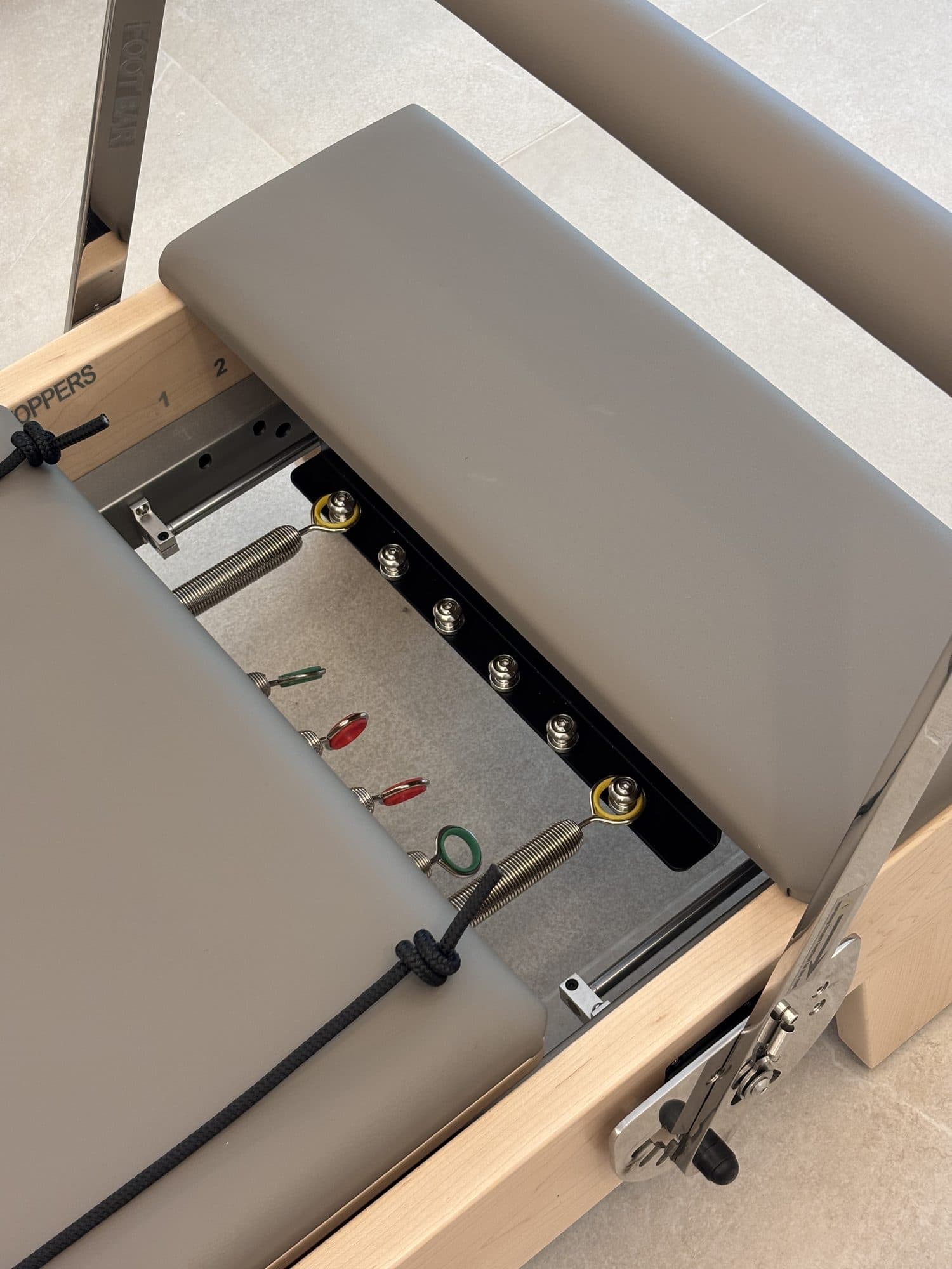 Colour-coded springs under the carriage of an Elite Reformer